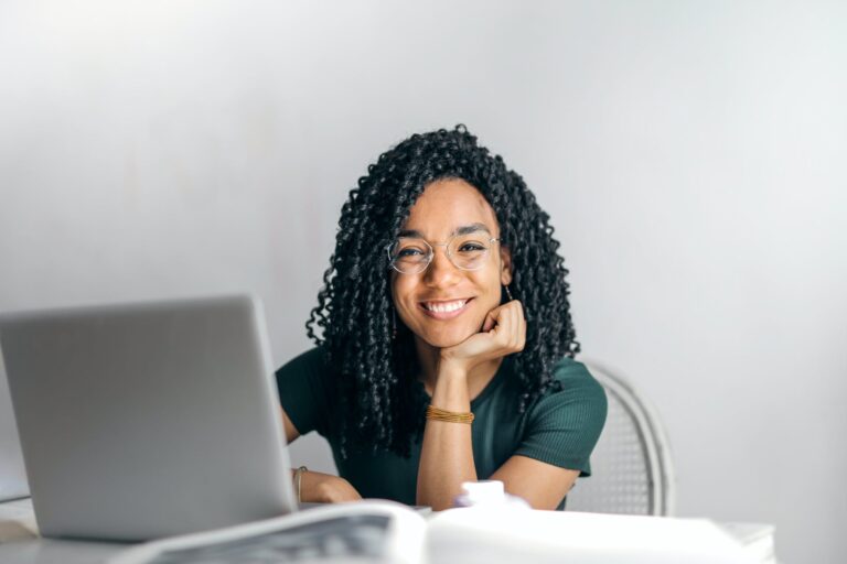 happy ethnic woman sitting at table with laptop