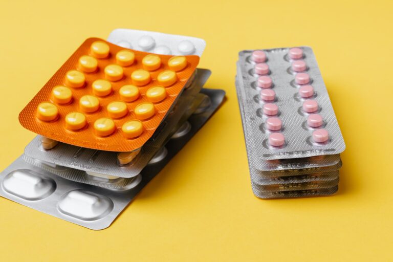 heaps of pills blister packs on yellow surface