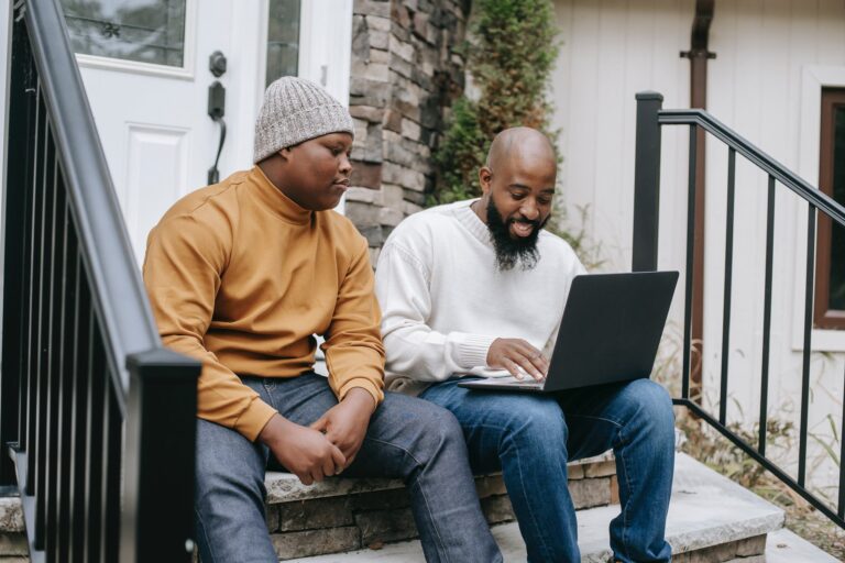 cheerful black businessman browsing laptop with son