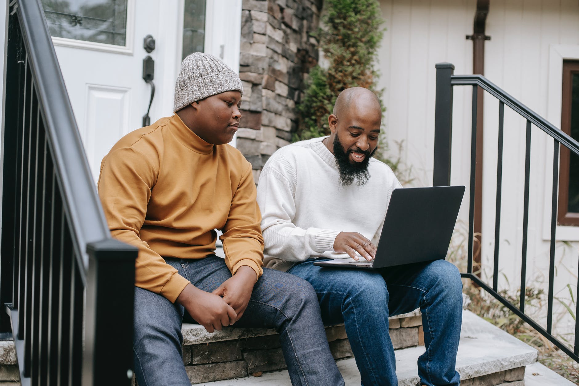 cheerful black businessman browsing laptop with son