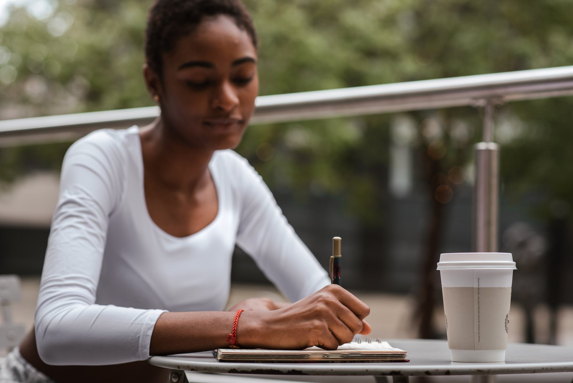 black woman with coffee and pen on terrace