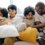 multiethnic family resting together on sofa with dog in living room