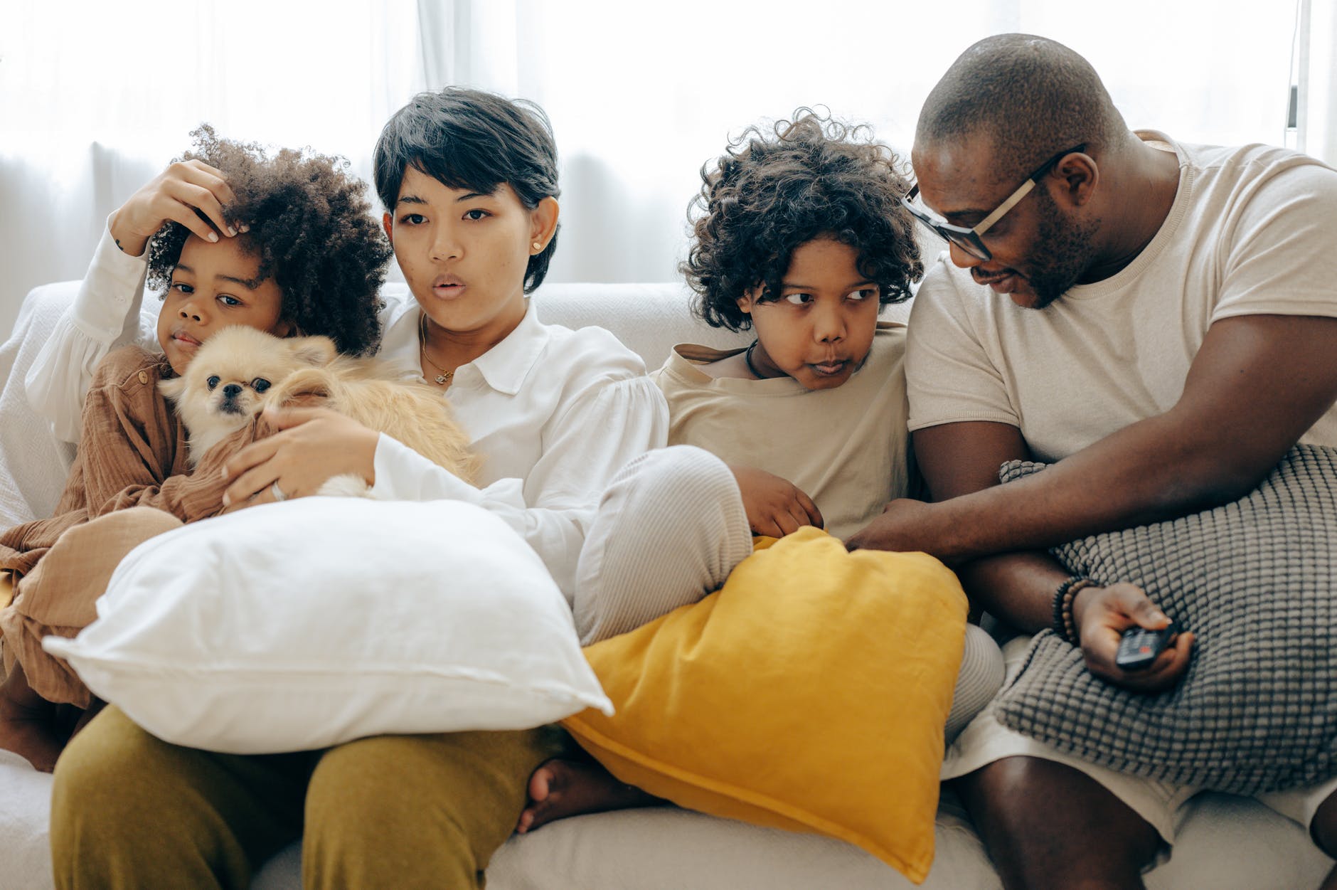 multiethnic family resting together on sofa with dog in living room