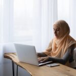 busy muslim lady working on laptop in light room