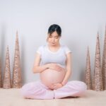 woman showing her baby bump while sitting on floor