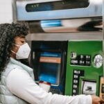 african american female in mask using ticket machine in subway