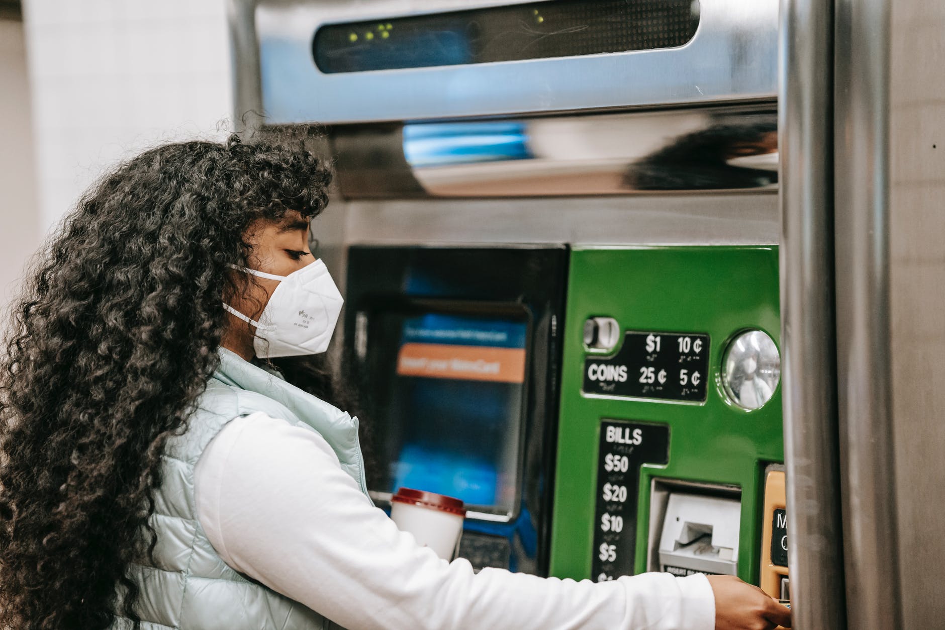 african american female in mask using ticket machine in subway