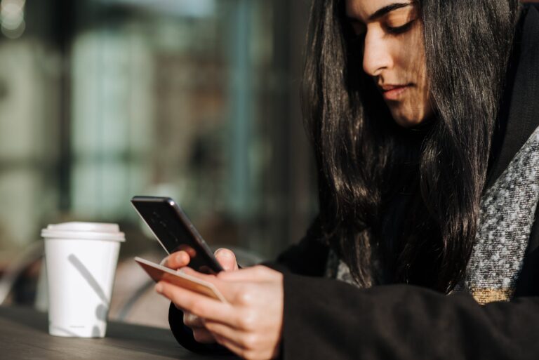 crop ethnic shopper making purchase on smartphone with debit card