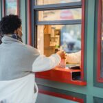 unrecognizable black men picking up order near window of store