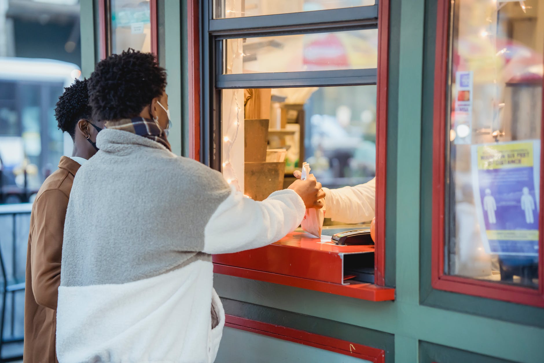 unrecognizable black men picking up order near window of store