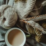 knitting supplies and cup of coffee placed on bed