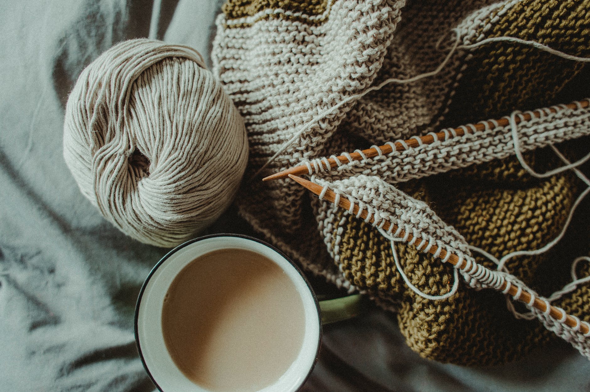 knitting supplies and cup of coffee placed on bed