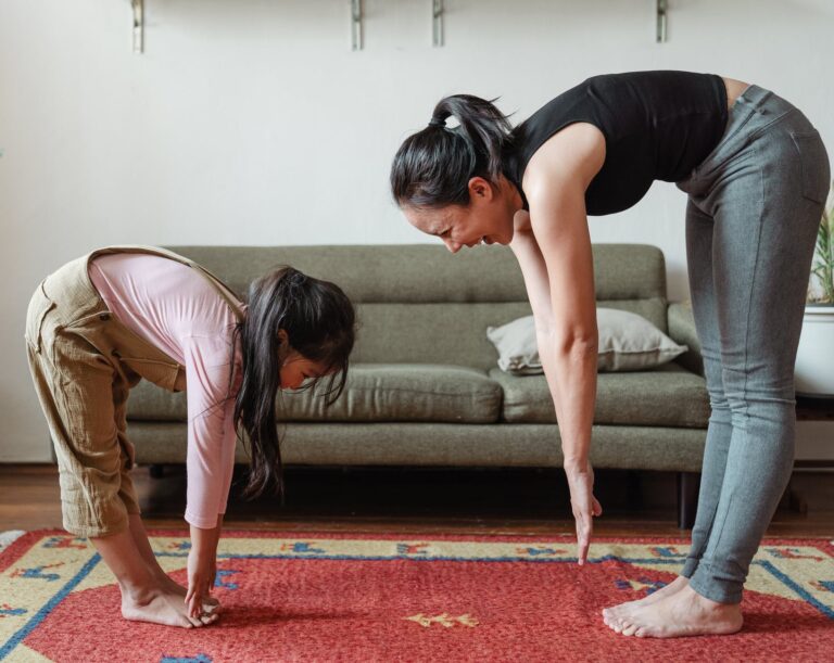 excited barefoot ethnic mother and cute girl doing stretching exercises together