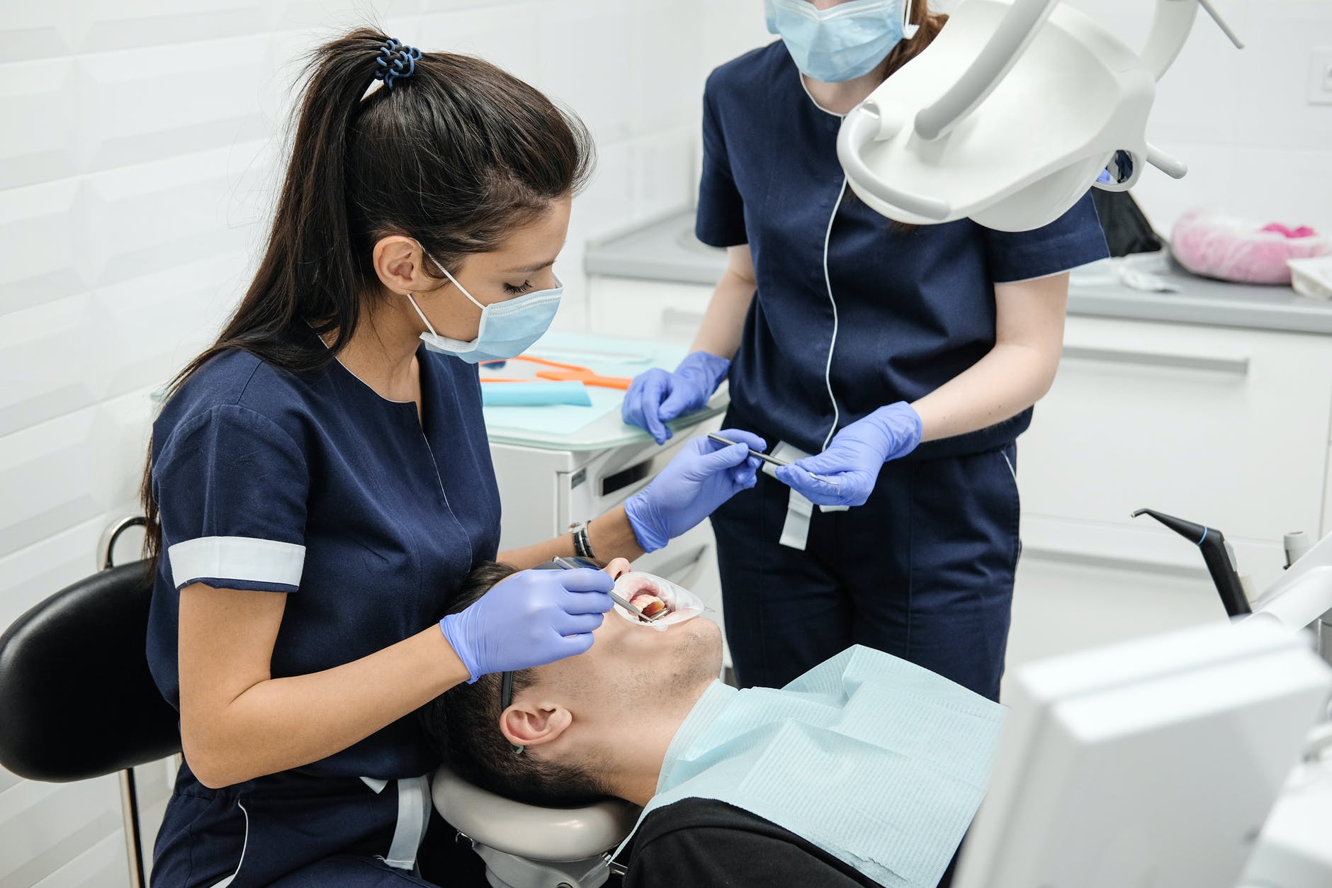 female dentist with assistant curing teeth of patient