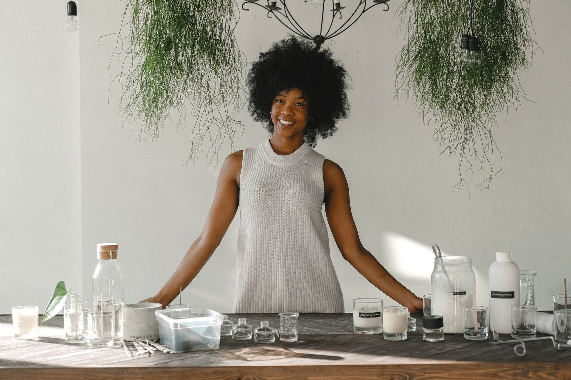 delighted black woman standing at table in workshop for making candles