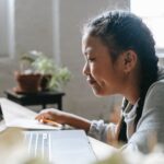 focused ethnic girl studying on laptop