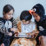 kids in costumes playing games with tablet computer