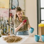 girl in brown jacket holding blue ceramic mug