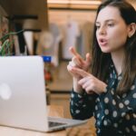 focused young woman having video call on netbook in modern workspace