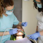 dentist with assistant treating teeth of patient