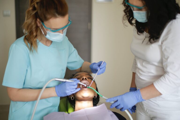 dentist with assistant treating teeth of patient