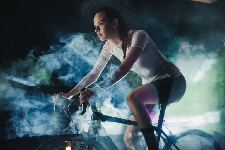 focused sportswoman riding bike in artificial smoke