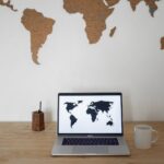 world map on wall and laptop near cup and container