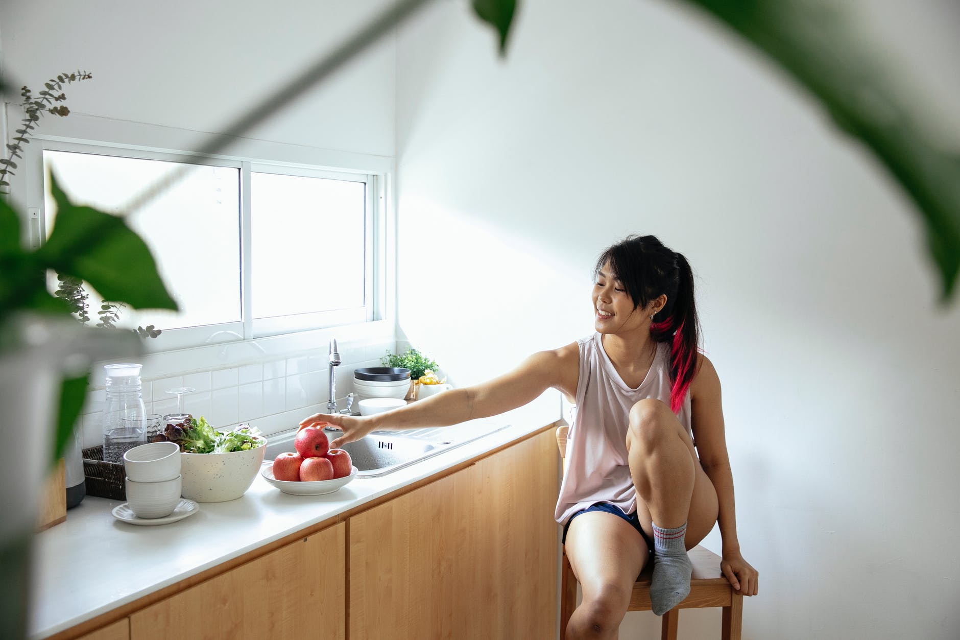 asian woman sitting on stool near counter in kitchen