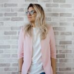 woman in pink cardigan and white shirt leaning on the wall