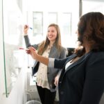two women in front of dry erase board