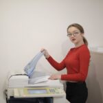 serious female office worker using printer in workplace