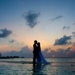 silhouette photo of man and woman kisses between body of water