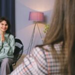 happy young woman smiling while talking to psychologist in modern office