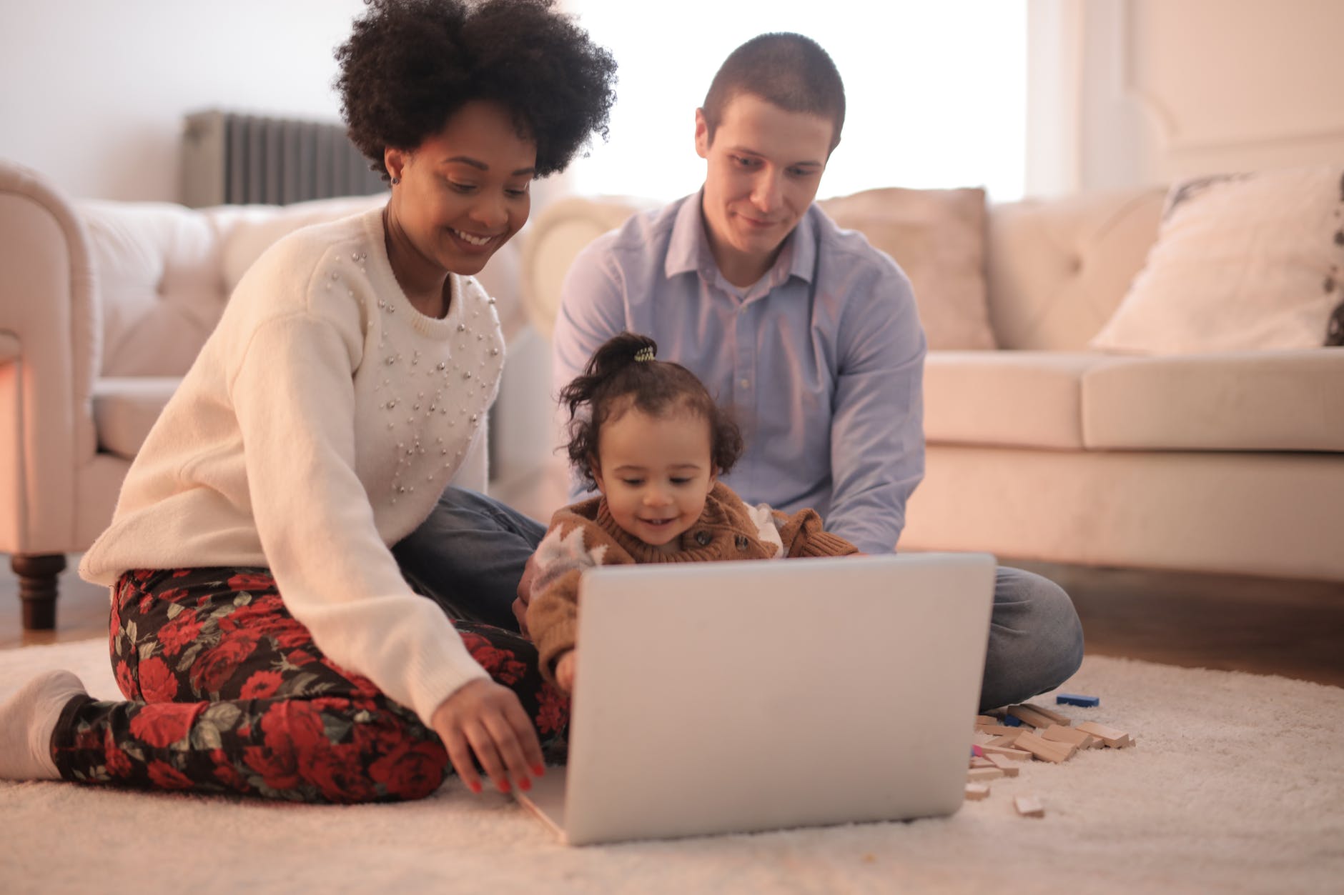photo of family sitting on floor while using laptop