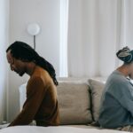 concerned black couple sitting on bed in misunderstanding