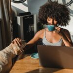 african american female freelancer using laptop and drinking coffee