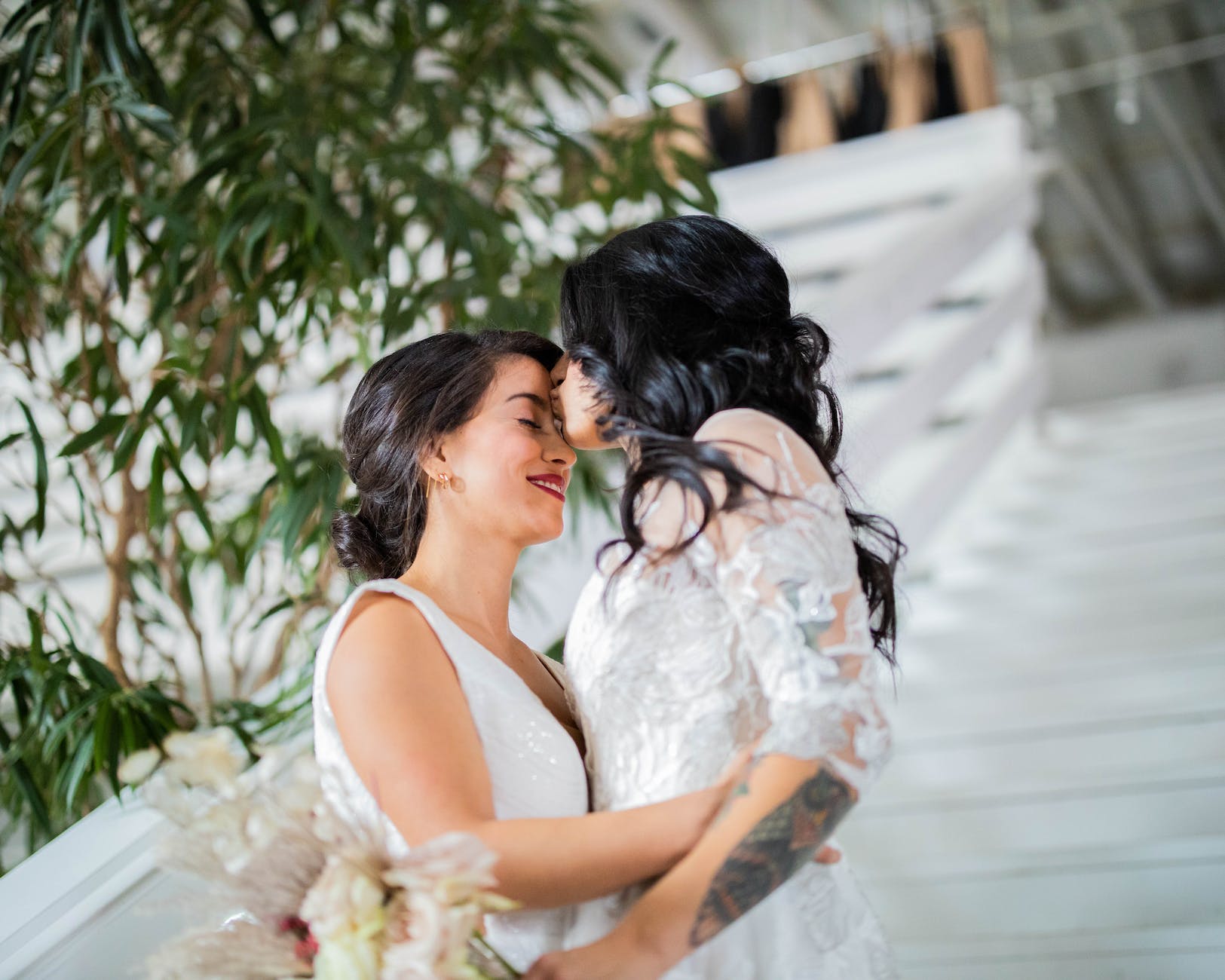 woman in white floral dress kissing woman in white dress