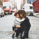 woman wearing black jacket holding girl