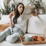 a woman reading a newspaper while having breakfast