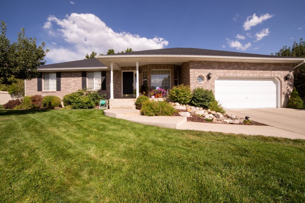 green grass lawn near white and brown house under blue sky