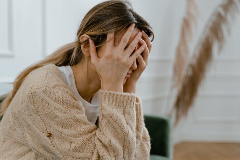 woman sitting with hands covering her face