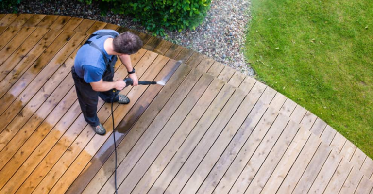 Man pressure washing a deck