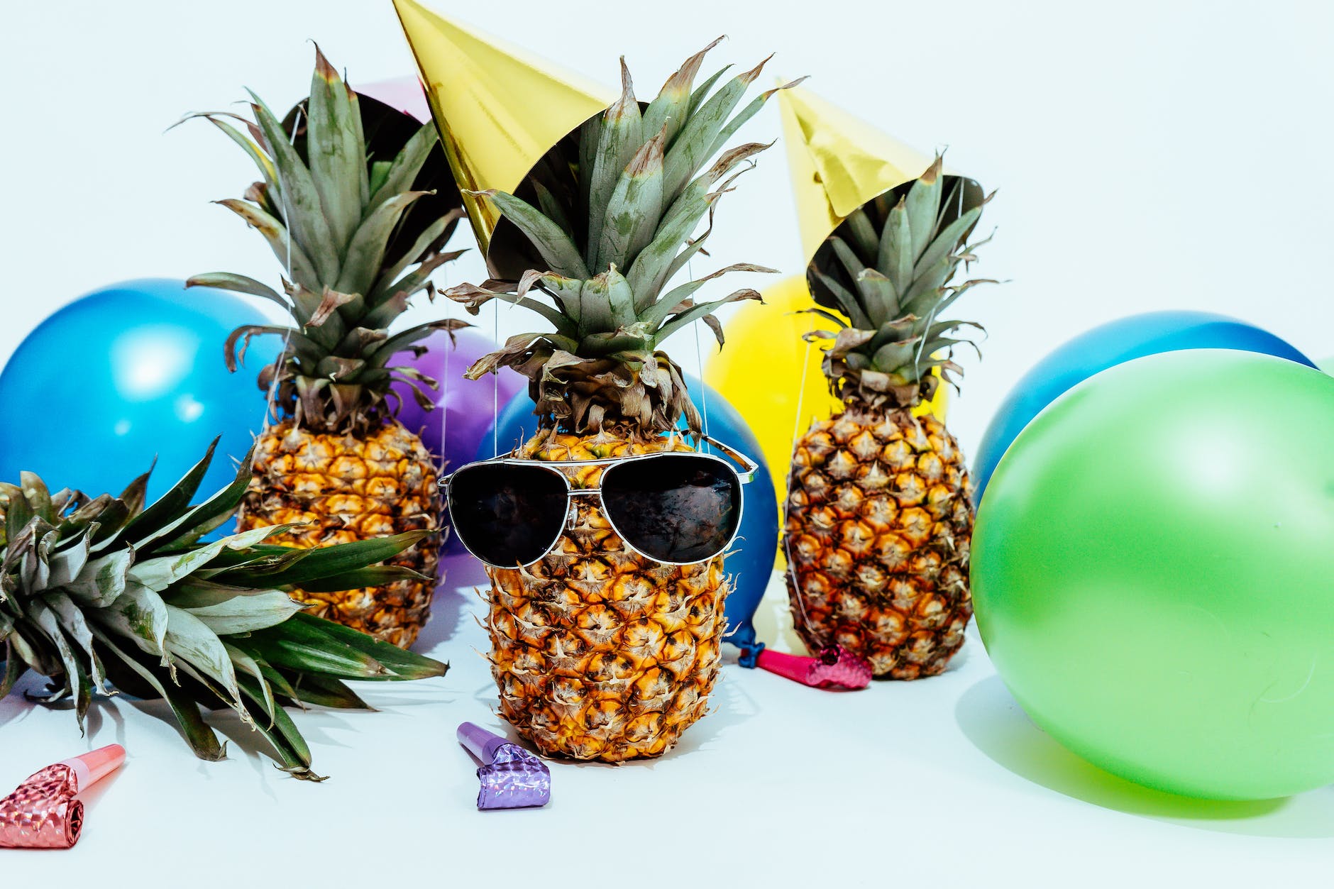 photo of three pineapples surrounded by balloons