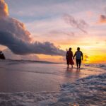 a couple walking at the beach during sunset