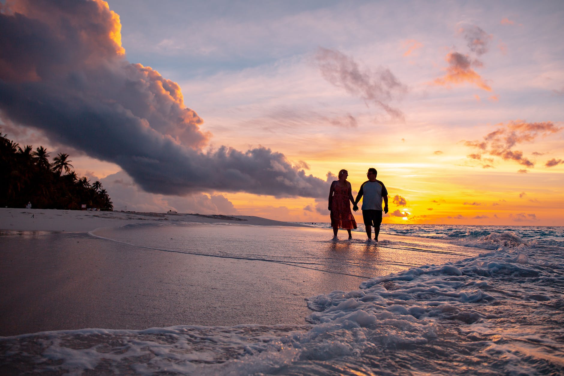 a couple walking at the beach during sunset