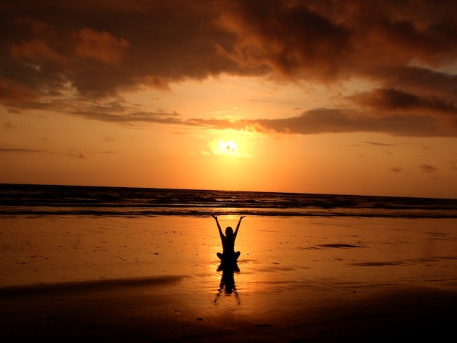A person meditating against a sunset