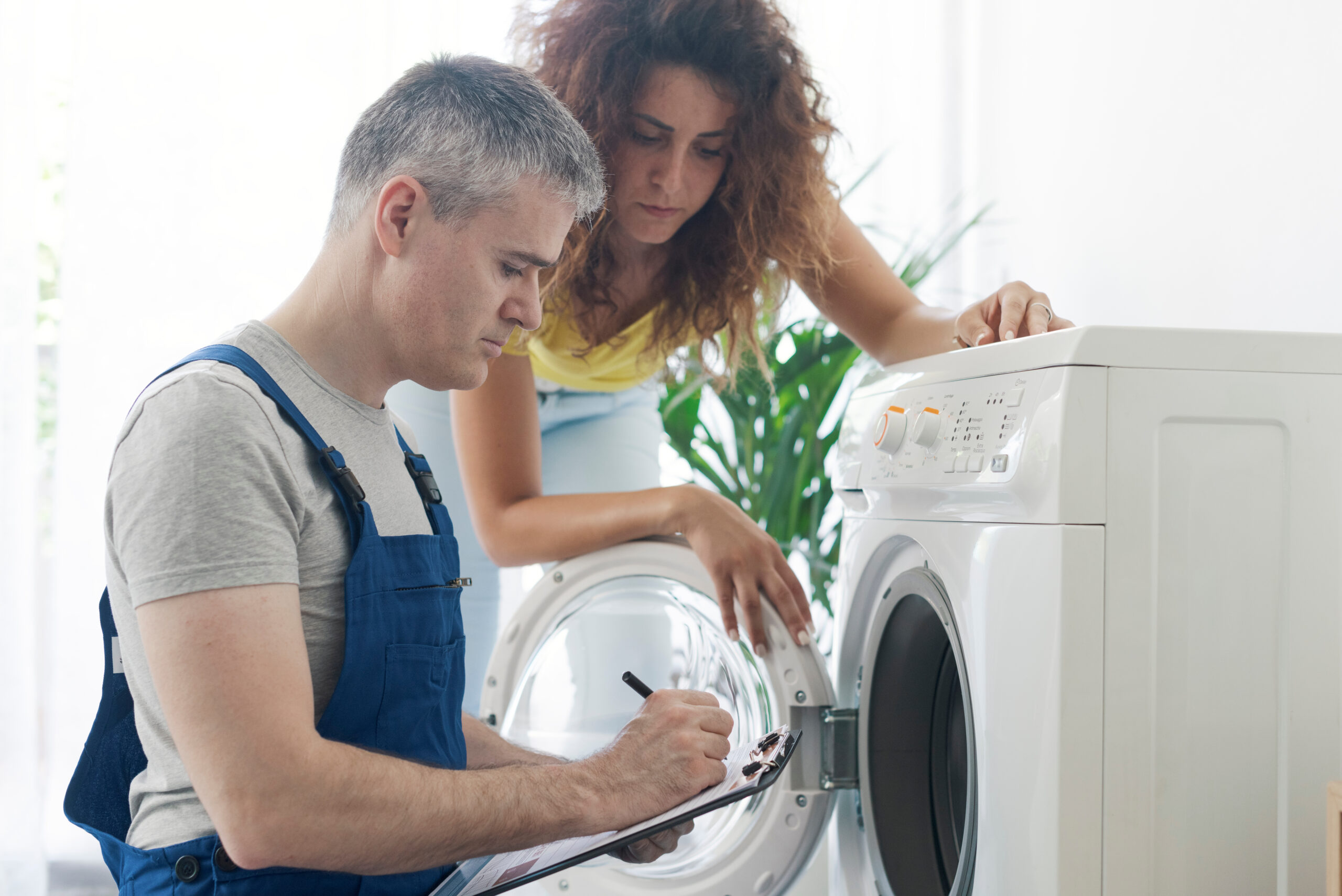 Two people working together to fix a washing machine