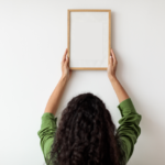 Woman hanging a frame on an otherwise blank wall