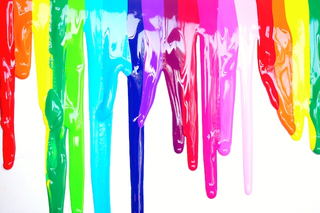Many colors of paint running down a white background