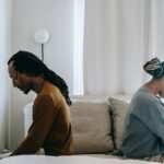 concerned black couple sitting on bed in misunderstanding